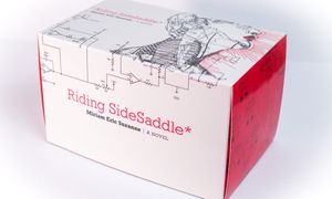 Riding SideSaddle* physical copy in a black, white, and red box